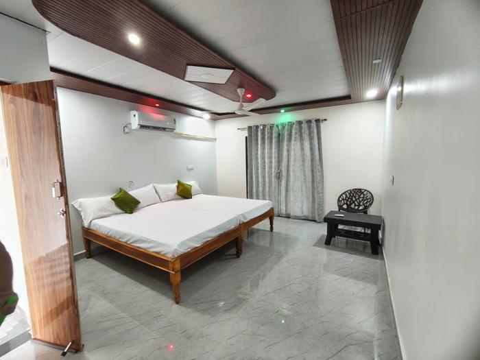 AC guest room with white bedding, green cushions, a table and a chair at the Nandai Gate stay.