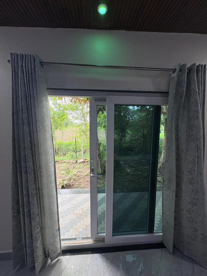 View through a sliding glass door toward the patio and greenery at the Nandai Gate stay.