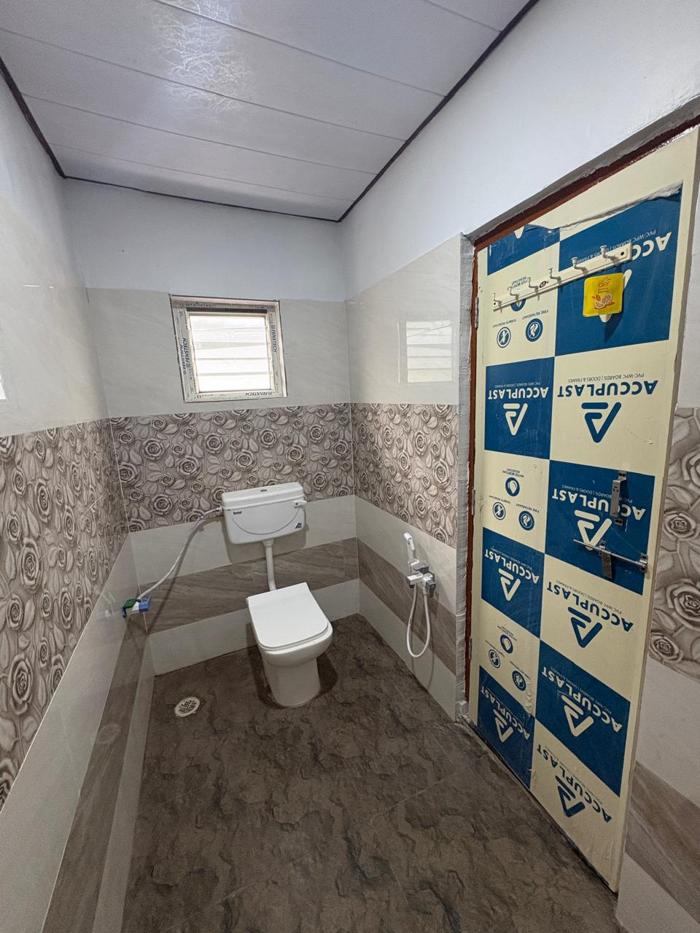 Attached bathroom with a western toilet and hand spray at the Nandai Gate stay.