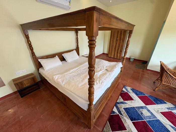 Wooden four-poster bed with bedside table and wardrobe at the Bhavankhori Gate stay.
