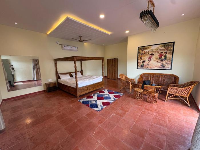 Wide view of the four-poster bed, wicker seating and mirror in a Bhavankhori Gate room.