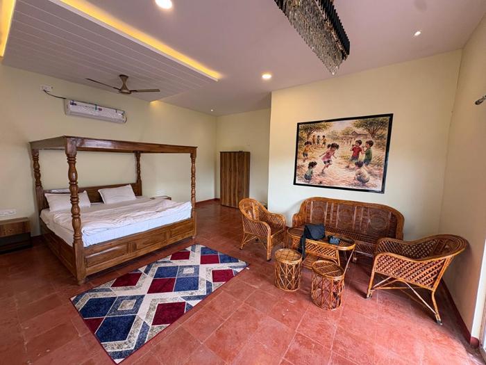 AC room with a wooden four-poster bed and wicker seating at the Bhavankhori Gate stay.